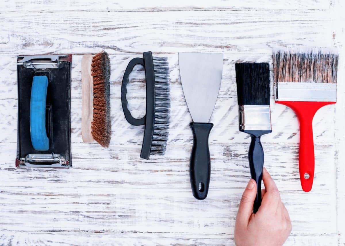 Flera olika penslar mot en vit trävägg