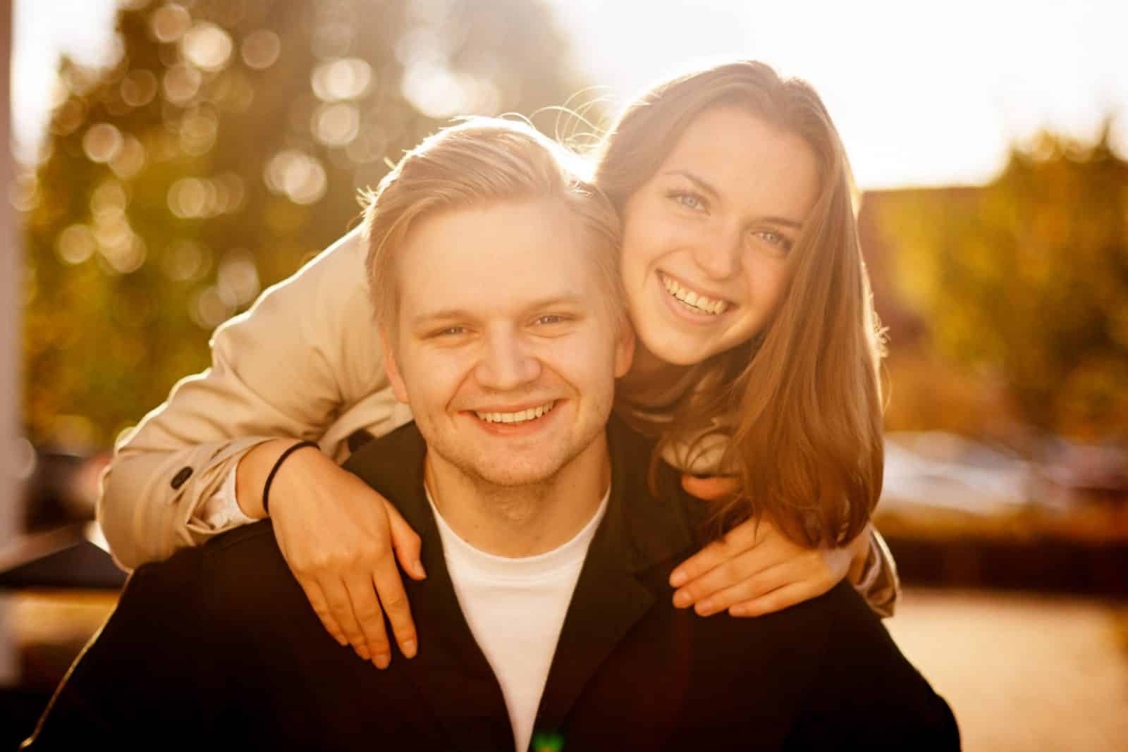 Lyckligt par tittar in i kameran, bakgrunden är varm och suddig