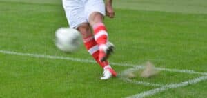 Ben som spelar fotboll och skjuter en boll framåt