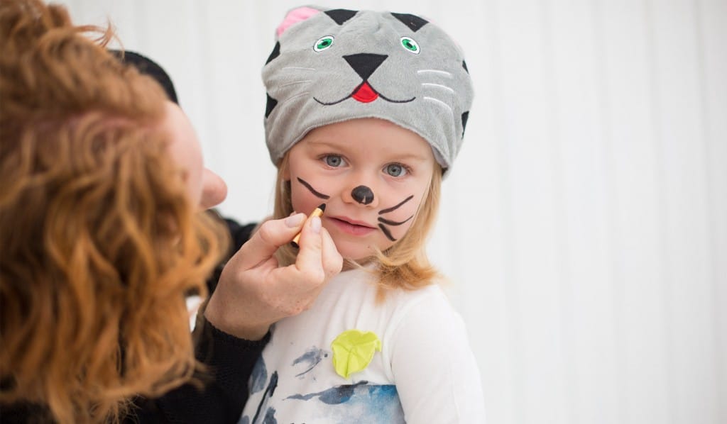 En vuxen sminkar ett barn som en katt