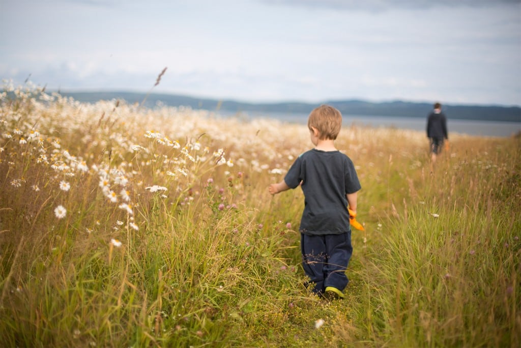 Ett barn som nyfiket tittar på blommor på väg till stranden